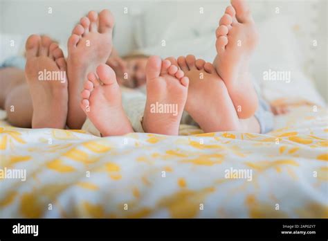 Three Pairs Of Bare Feet In A Row Different Sizes On A Bed Stock Photo