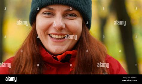 Young Girl In Warm Clothes Looks Into The Camera And Smiles Outside In