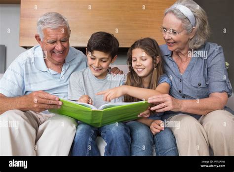 Happy Grandparents And Grandkids Looking At Album Photo In The Living