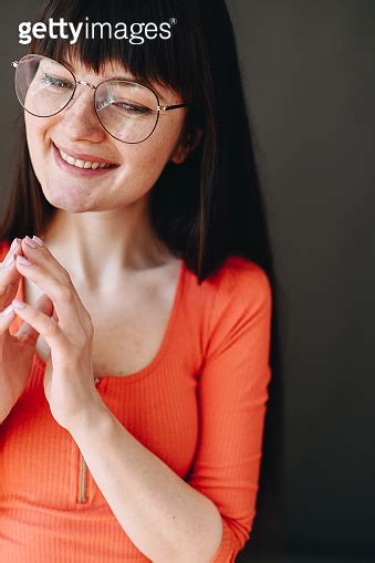 portrait of smiling girl in glasses who folded her fingers in front of her and looks down