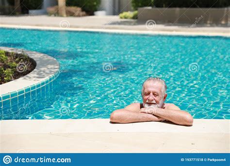 Happy Elderly Caucasian Swimming In Pool During Retirement Holiday With