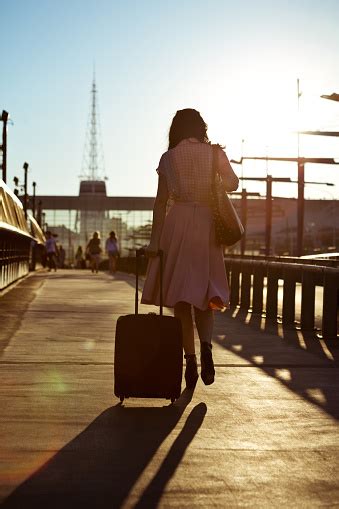 Young Woman Walking Sidewalk And Carrying Suitcase Stock Photo