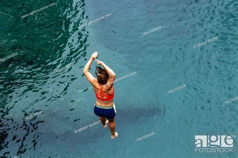 A Young Woman Jumps Into The Blue Pools Near Makarora Mt Aspiring