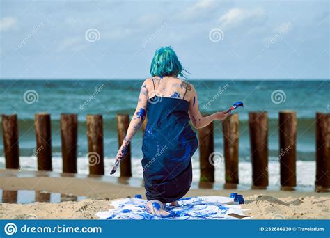 Artistic Blue Haired Woman Performance Artist Smeared With Blue Gouache Paints Dancing On Beach
