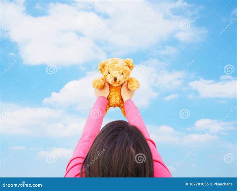 Back View Of Asian Girl Holding Teddy Bear Toy Over Blue Sky Stock