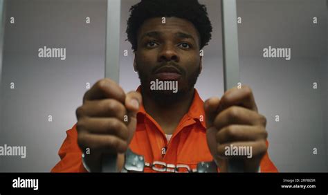 African American Prisoner In Orange Uniform Keeps Hands In Handcuffs On