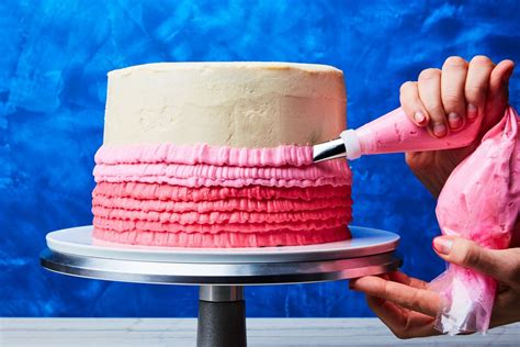 A Person Is Decorating A Cake With Icing And Pink Ruffles On It