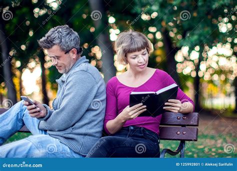 Portrait Of Couple Sitting Outside Woman Reading A Book Man Us Stock Image Image Of Book