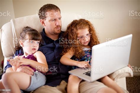 Color Image Of Two Babes Looking At Computer With Dad Stock Photo