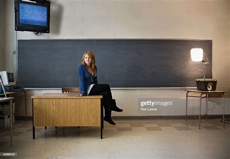Teen Girl Sitting On Teachers Desk In Classroom Photo Getty Images