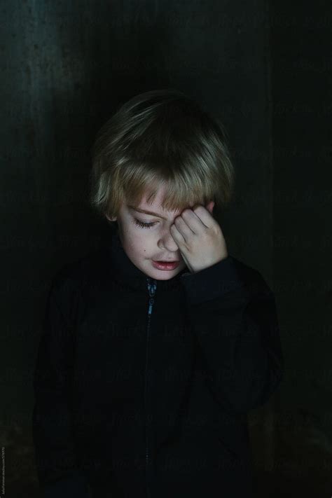 Low Light Painterly Image Of A Young Boy Rubbing His Eye By Stocksy