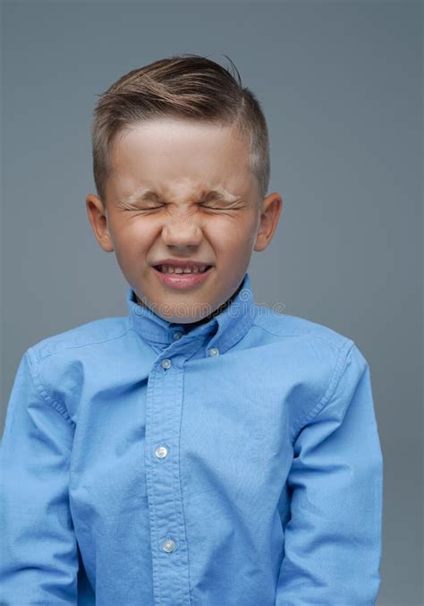 Displeased Little Boy Dressed In Blue Shirt Against Grey Background