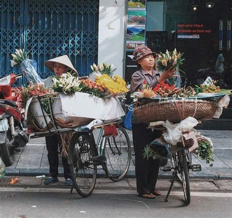 Two People On Bicycles With Baskets Full Of Flowers