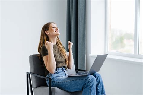Overjoyed Woman Sitting In Armchair With Laptop Celebrating Huge Online