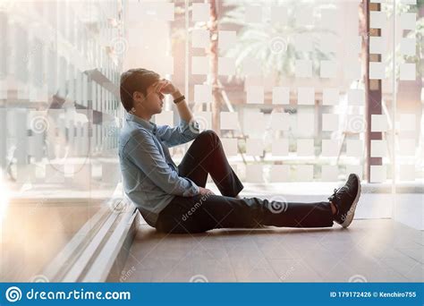 Sad Man Sitting On The Floor By Window At Office Walkway Feeling