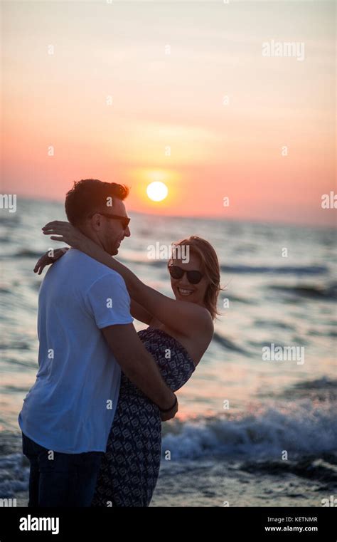 couple of lovers stands having embraced on the seashore sunset sea waves romantic rendezvous
