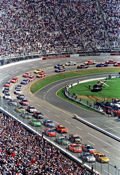 An Aerial View Of A Race Track With Cars Driving On It And People