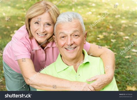 Portrait Of Happy Mature Woman Hugging Her Husband In The Park Stock