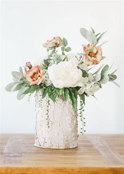 A White Vase Filled With Flowers On Top Of A Wooden Table