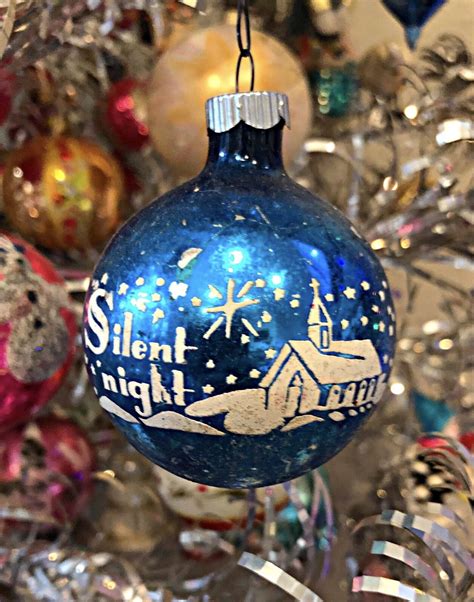 A Blue Ornament Hanging From The Side Of A Christmas Tree Filled With