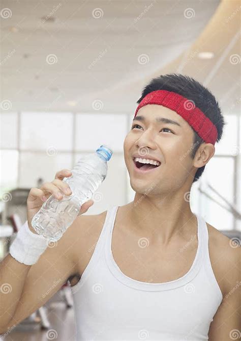 Portrait Of Smiling Young Man Drinking From Water Bottle At The Gym