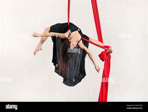 Full Body Of Graceful Barefooted Young Female Dancer Performing Arch On Hanging Red Aerial Silks