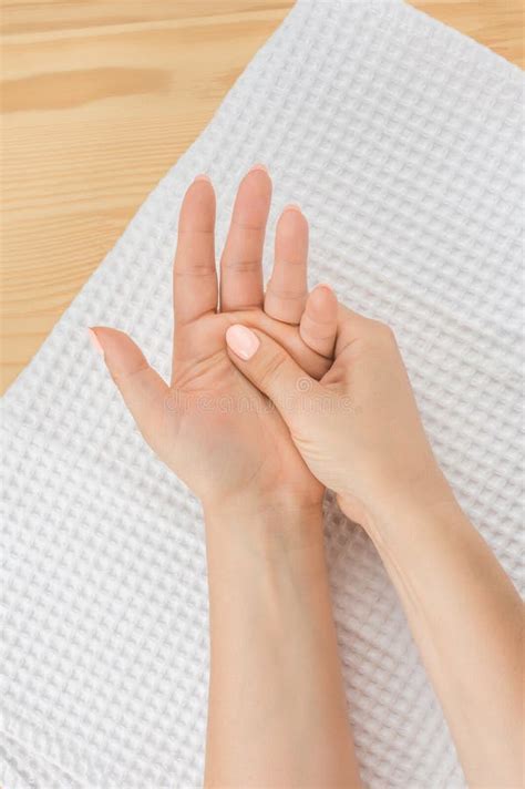 One Woman Hand Massages The Other Hand Lying On A White Towel With The Open Palm Up Closeup