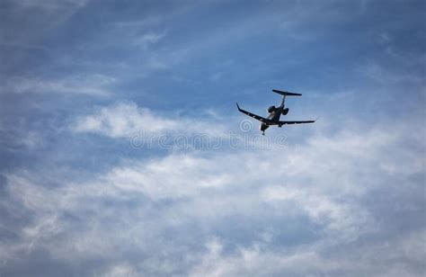 Private Jet With Landing Gear Down Flying Across Blue Sky With White
