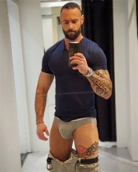 A Man With Tattoos On His Arm And Leg Is Taking A Selfie In The Mirror