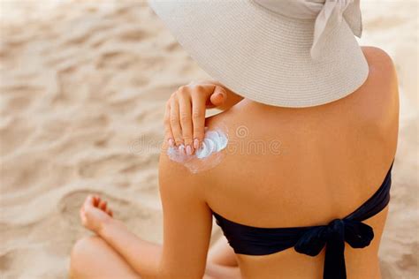 Woman Putting Sunblock Lotion On Shoulder Before Tanning During Summer Holiday On Beach Sun