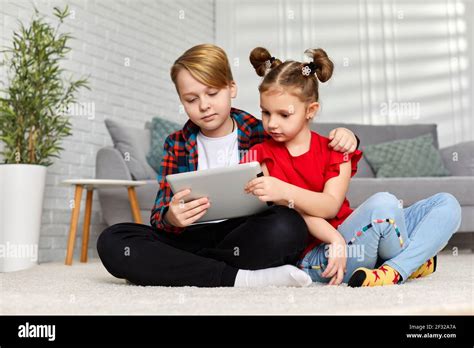 Cute Brother And Sister With Tablet Lying On Floor At Home Stock Photo
