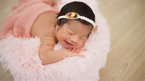 Smiley Cute Baby Girl Is Sleeping On Woolen Bed Wearing White Headband