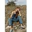 Caucasian Woman Wearing Overalls Sitting In Rocky Field  Stock Photo
