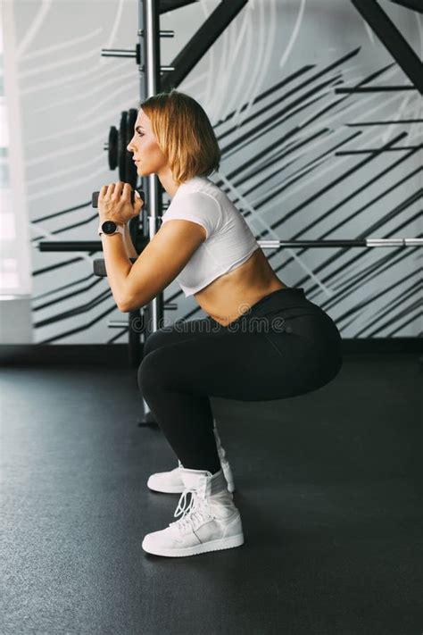A Sporty Girl Performs Squats With Dumbbells During A Workout In The Gym Sports Fitness Body