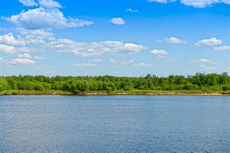 Summer Sunny Landscape With A Green River Bank And Blue Sky Stock Photo