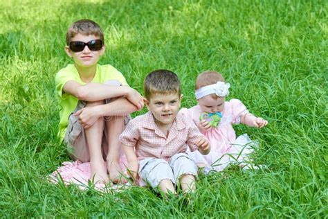 Three Children Sit In Grass Playing And Having Fun Stock Image Image