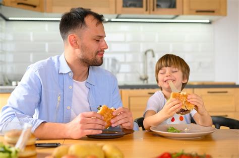 Pai E Filho Comendo Deliciosos Hambúrgueres Foto Grátis