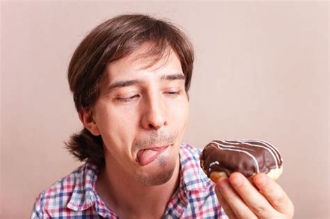 Premium Photo A Man Licks His Lips On A Chocolate Donut