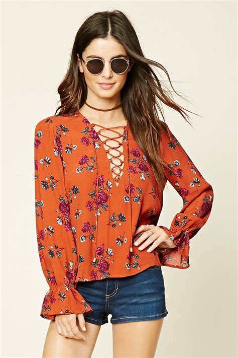 a woven top featuring an allover floral print lace up front and long ruffled sleeves