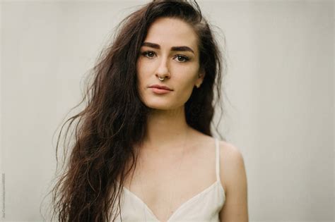 Female With Long Curly Dark Hair And Septum Nose Piercing With Cream Background And Cream