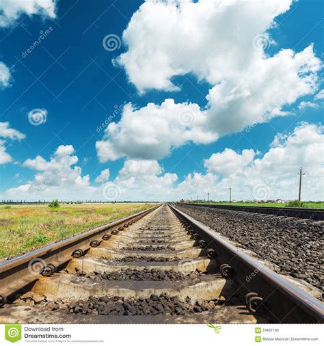 Railroad To Horizon Closeup Under Clouds In Blue Sky Stock Photo
