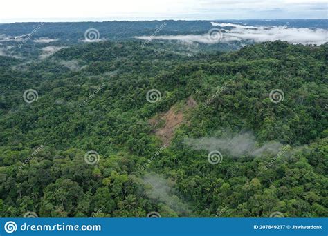 Aerial View Of A Green Tropical Rainforest In A Hilly Area With Clouds