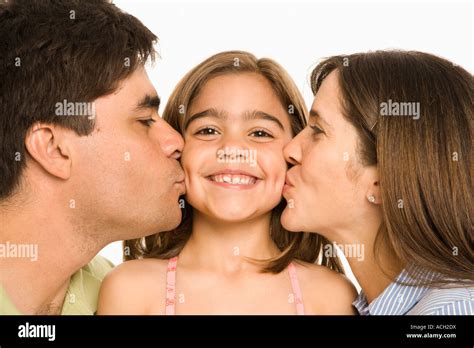 Mother And Father Kissing Smiling Daughter On Opposite Cheeks Stock