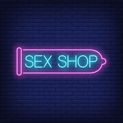 セックスショップのネオンサイン。レンガの壁にピンクのコンドーム。夜の明るい広告。 プレミアムベクター