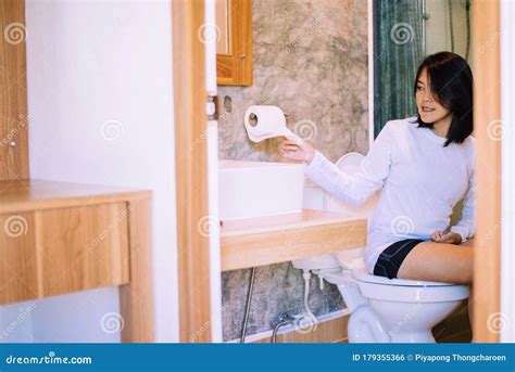 Young Asian Woman Using Toilet Paper And Using Toilet In Morning At