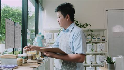 Asian Male Shopkeeper Checks Stock Of Natural Organic Products At