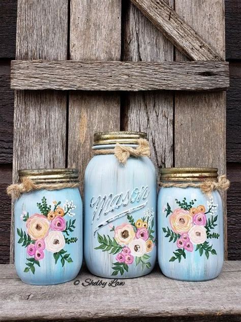 Three Mason Jars With Painted Flowers On Them