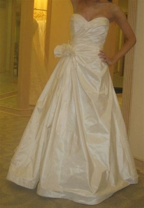 A Woman In A White Wedding Dress Posing For The Camera With Her Hand On