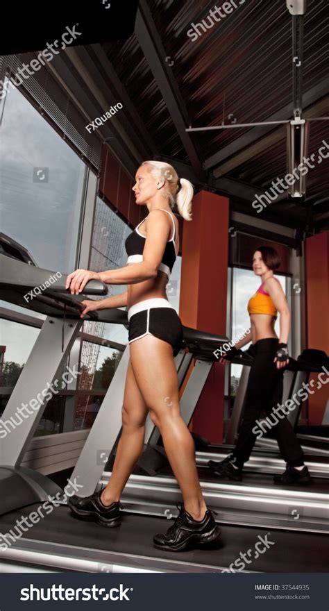 Portrait Of Two Attractive Girls Doing Exercise On Treadmill Stock