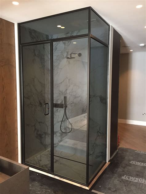 A Glass Shower Stall In A Bathroom With Marble Walls And Flooring On The Side